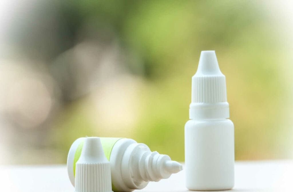 Two bottles of eye drops on a counter with one sitting straight up and the other on its side with the lid off.