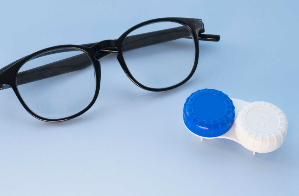 A pair of glasses with black frame and pair of contact lenses in a light blue background.
